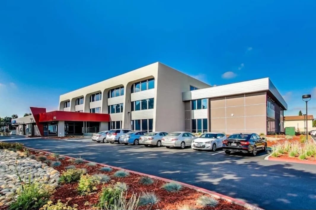 Wide exterior view of Sola Pavilion at 1245 S. Winchester Blvd., San Jose — modern building with red entrance canopy